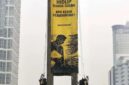 TUNTUTAN. Aktivis Greenpeace membentangkan spanduk protes setelah berhasil memanjat Patung Selamat Datang di kawasan Bundaran HI, Jakarta Pusat, Selasa (20/10/2026). Aksi tersebut memunculkan pertanyaan mengenai pengawasan kepolisian di sekitar ikon Ibu Kota itu. (Istimewa/Redaksi BBI/Jakarta)